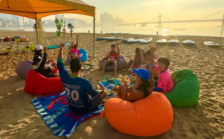 People sitting around on the sandy beach eating breakfast