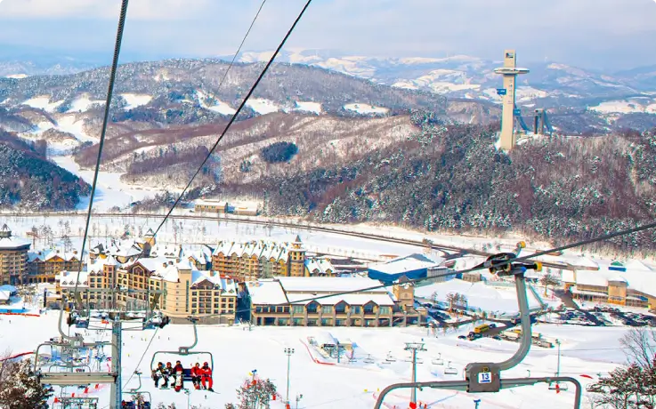 Skiers and snowboarders riding a lift up snow-covered slopes at Alpensia Ski Resort.