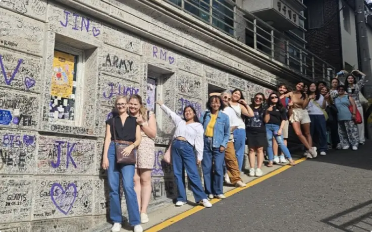 ARMY posing in front of Cheonggu Building's wall, covered with messages from BTS fans.