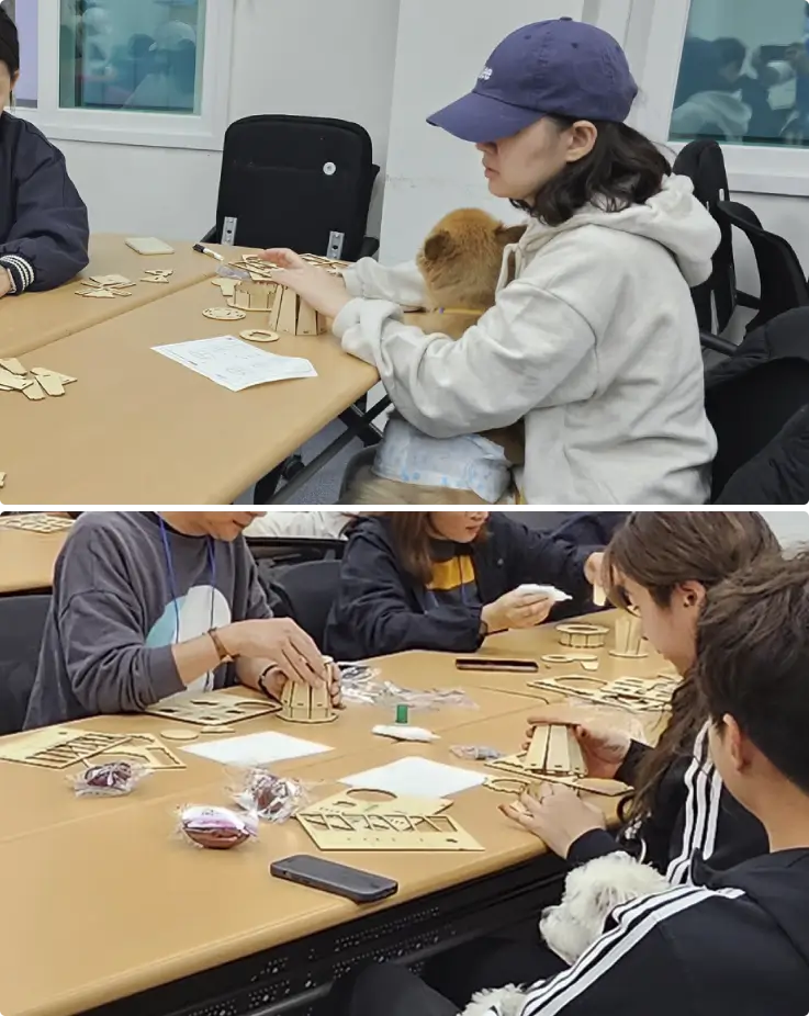 A family in a woodworking class, crafting a pet food bowl stand, with their dogs on their laps.