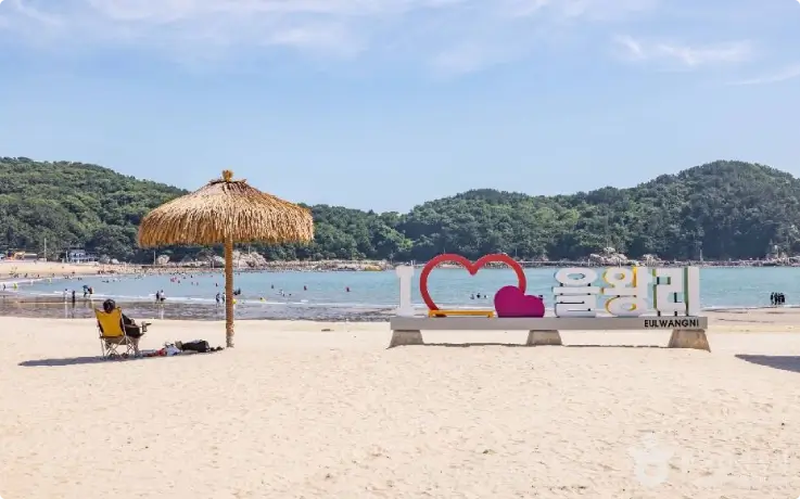 Visitors enjoying the wide sandy beach at Eurwangni Beach.