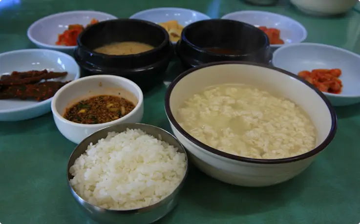 Traditional Korean meal featuring Chodang sundubu soft tofu stew with various side dishes and rice.