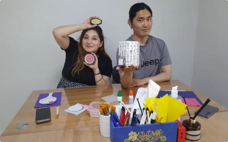 Participants crafting hand mirrors and coasters using hanji paper and mother-of-pearl materials.