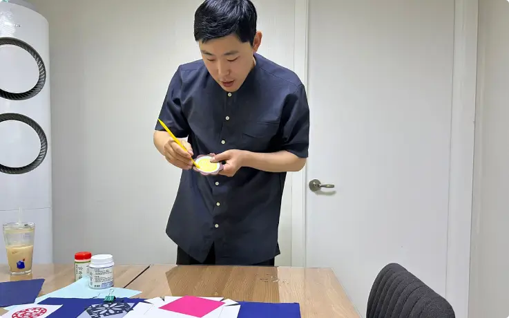 Crafting instructor demonstrating hanji and mother-of-pearl techniques to participants.