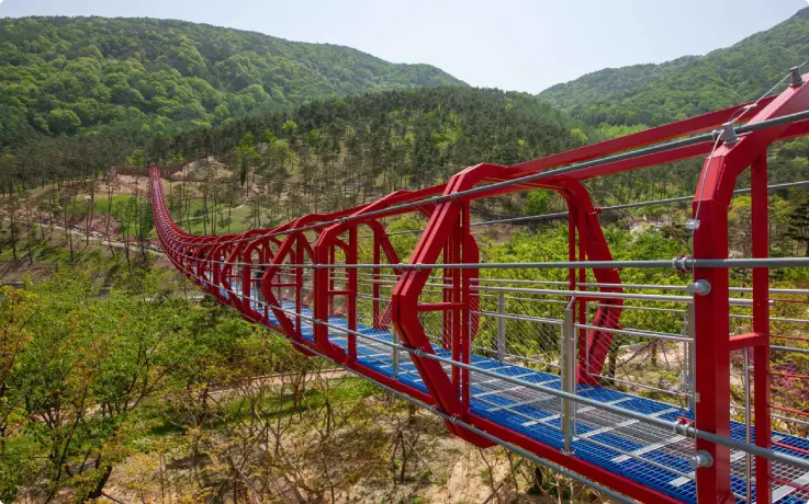 Traditional style Mureunggyo Bridge spanning over a green forested valley