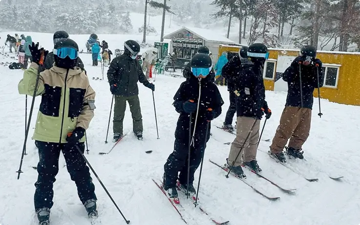 Skiers lined up during a ski lesson, wearing ski gear on a snowy slope at Oak Valley Ski Resort.