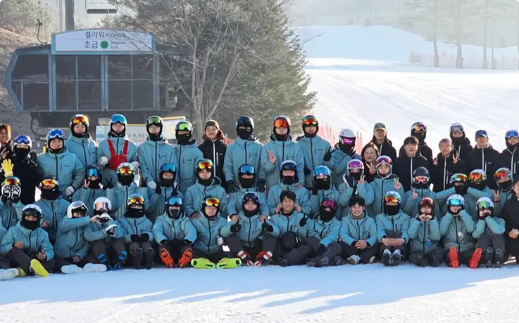 Group of students and instructors posing together on the snow after a ski lesson at Oak Valley Ski Resort