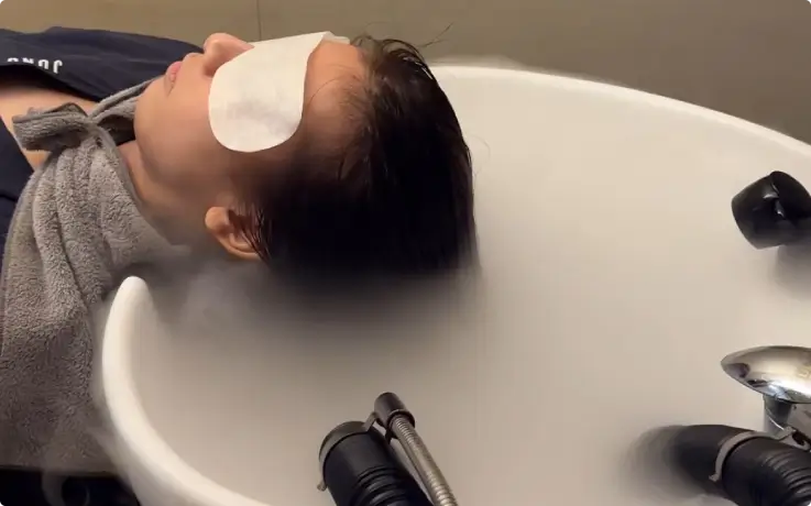 Customer relaxing on a head spa bed with steam therapy.