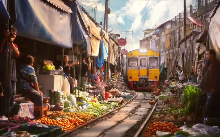 Stalls set up on both sides of an active train track at Maeklong Railway Market.