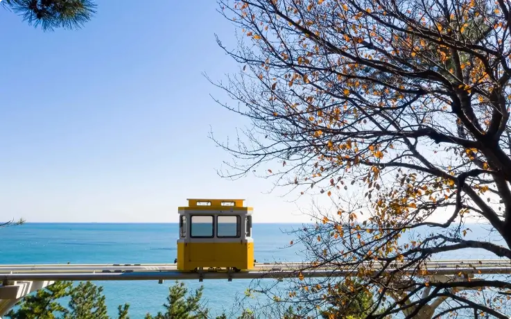 Blueline Park Sky Capsule gliding above the Haeundae coastline in daylight