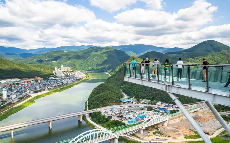 Visitors walking on the glass-bottom walkway at Mancheonha Skywalk in Danyang