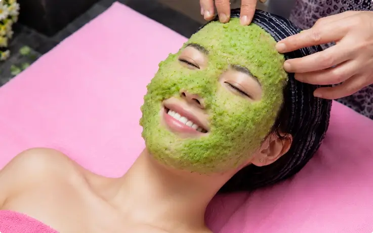 Visitor receiving a cucumber pack on the face at a women's-only mud massage spa in Myeongdong