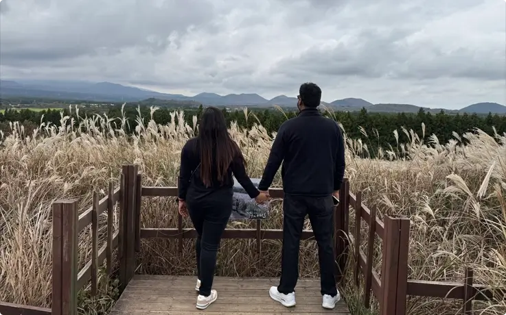 Visitors taking photos with a silvergrass backdrop at Sangumburi Crater on Jeju Island