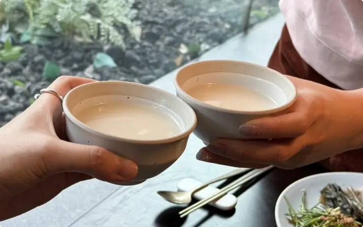 Visitors drinking makgeolli at a Joseon-style Korean liquor tasting and storytelling experience in Seoul