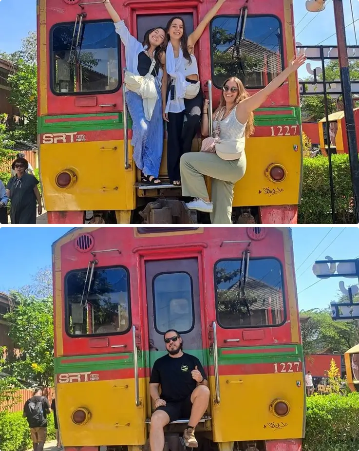 Visitors taking photos with a train at Maeklong Railway Market
