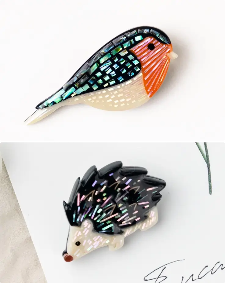 A bird-shaped brooch on top, hedgehog on the bottom made with mother-of-pearl.