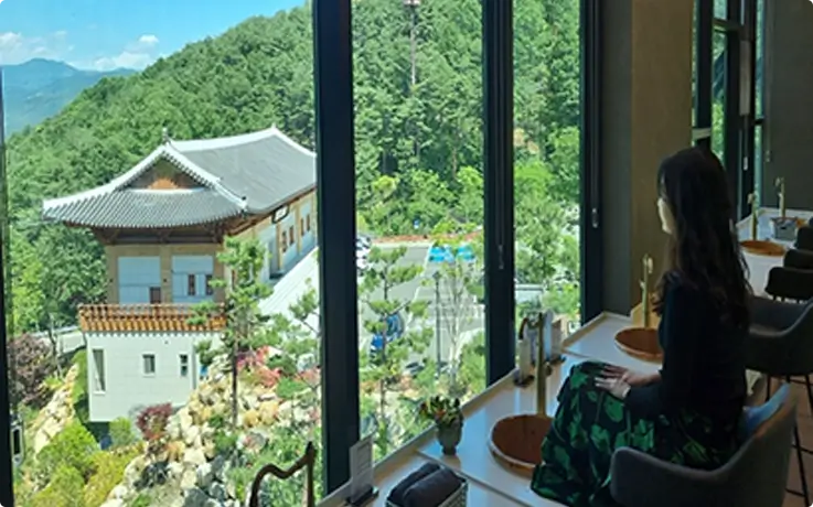 visitor trying traditional Korean herbal tea during foot bath experience at Donguibogam Village in Sancheong