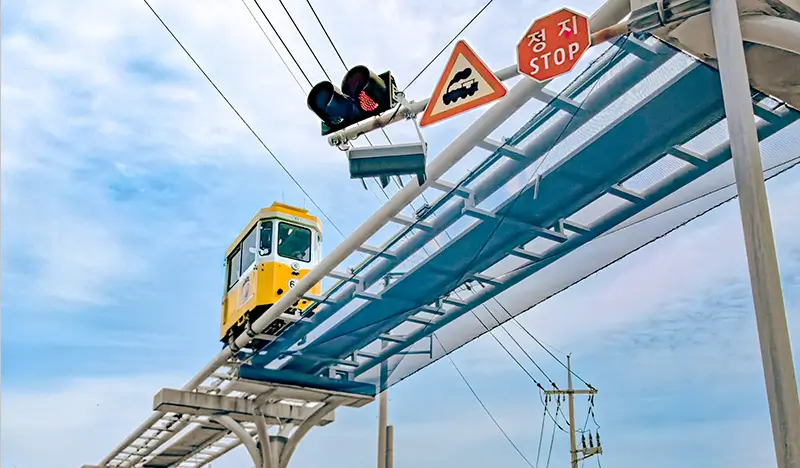 Elevated coastal sky capsule transit crossing above roadway.