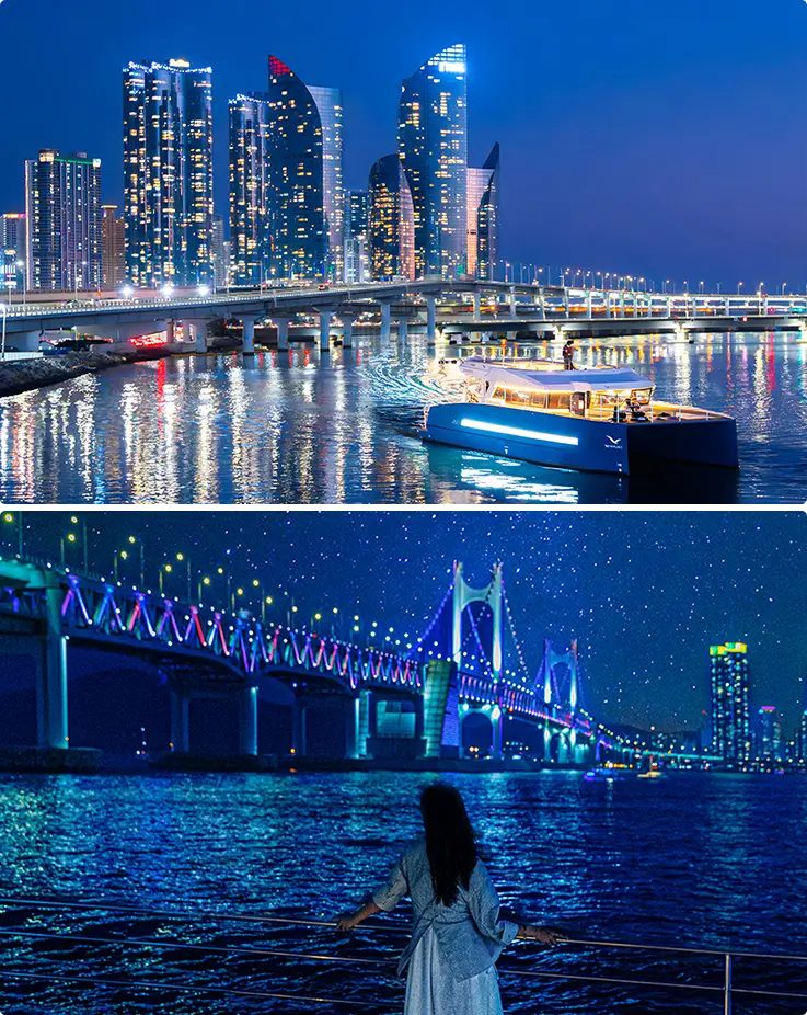Yacht cruises past glittering skyscrapers and a rainbow-lit suspension bridge at night.