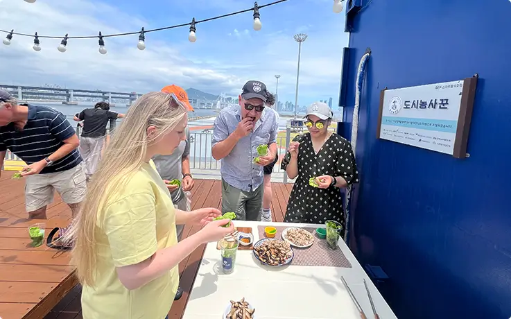 Guests taste freshly harvested produces outdoors beside the scenic smart farm container.