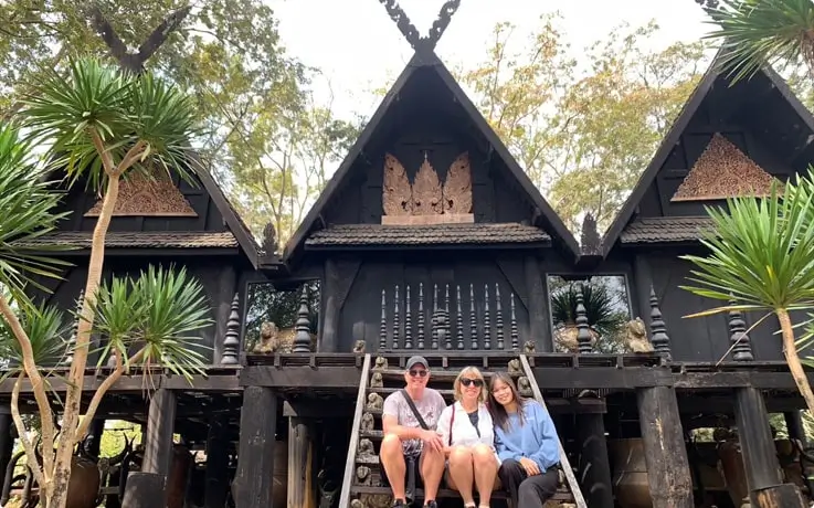People sitting on the stairs of Black House in Chaing Rai