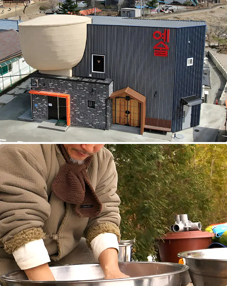Hands knead fermenting rice mash outdoors, crafting authentic makgeolli beside a striking modern brewery building.