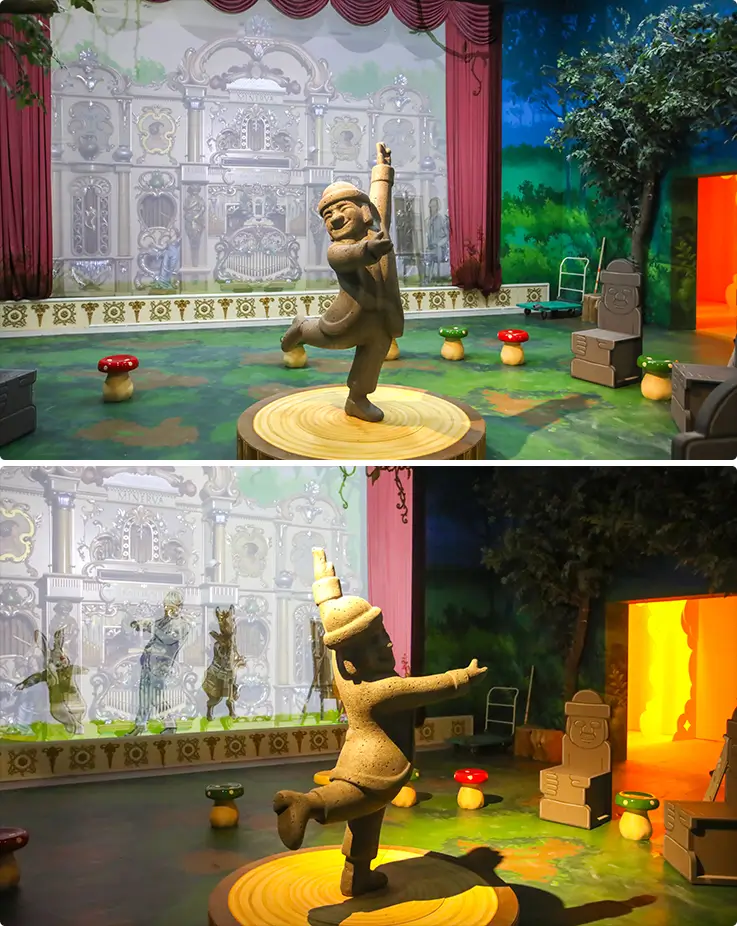 Baksal2: K-Island Jeju's interactive zone featuring dancing Dolharubang figures set against a whimsical theatrical stage backdrop.