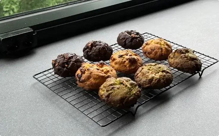 Freshly baked Levain cookies in assorted flavors cooling on a wire rack.