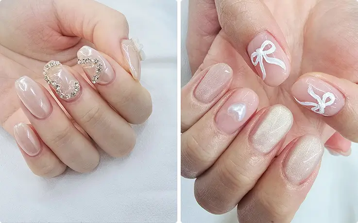 Elegant Korean nail art featuring rhinestone heart charm and delicate white ribbon bow designs.