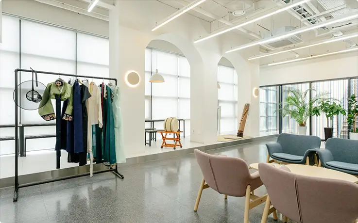 Bright White Room lounge featuring hanbok rack, traditional Korean instruments, and relaxed seating for guests.