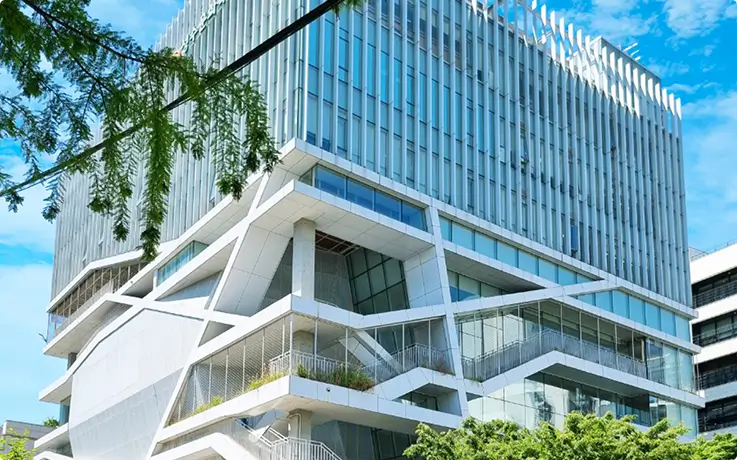 Angular modern building showcasing striking white architecture with sleek glass paneling details.
