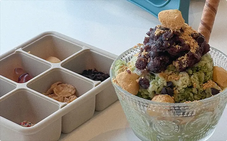 Matcha shaved ice piled high with red bean, rice cakes, and cookie crumble.