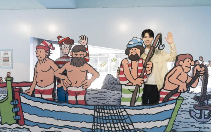 Guest waves from a boat photo cutout with Wally and fisherman characters.