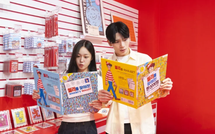 Couple browses Where’s Wally? books beside merchandise in the red souvenir shop.