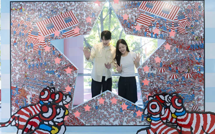 Couple poses through a star-shaped frame at Where’s Wally? in Hongdae photo zone.