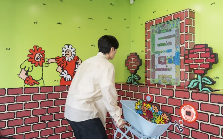 Guest pushes a wheelbarrow of flowers in a brick garden game mission.