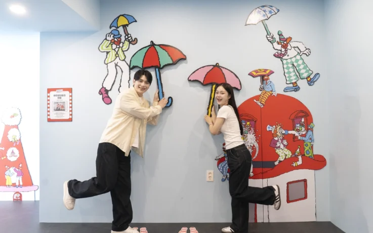 Couple balances on one leg in an umbrella and clown photo zone.
