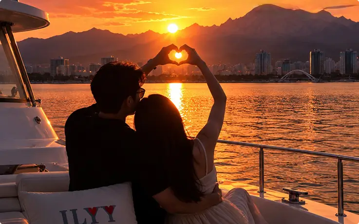 Pasangan romantis membentuk simbol hati saat matahari terbenam dalam pelayaran yacht di Sokcho.