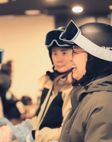 Smiling skiers in helmets and goggles getting ready inside the exclusive guest lounge.