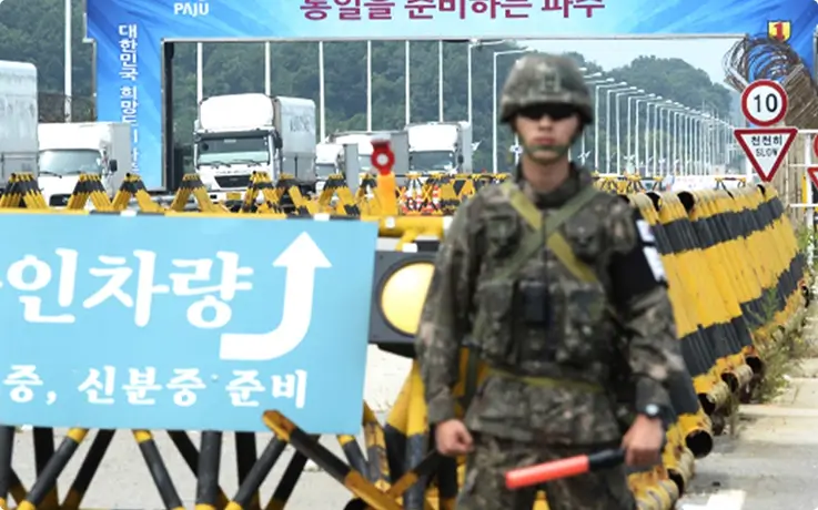 Soldier guarding the Civilian Control Line checkpoint near the Paju DMZ, with trucks waiting behind.