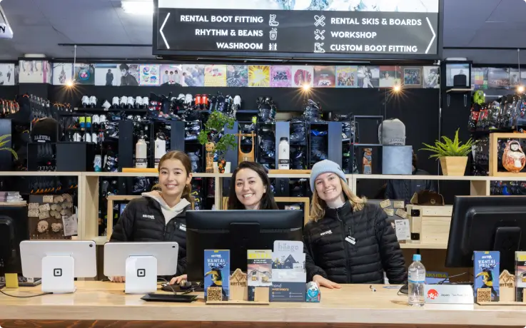 Friendly staff at the counter of Rhythm Wadano Hakuba ski rental shop.