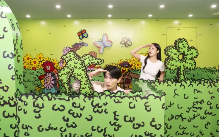 Couple peeks over a green hedge maze in a flower garden mission.